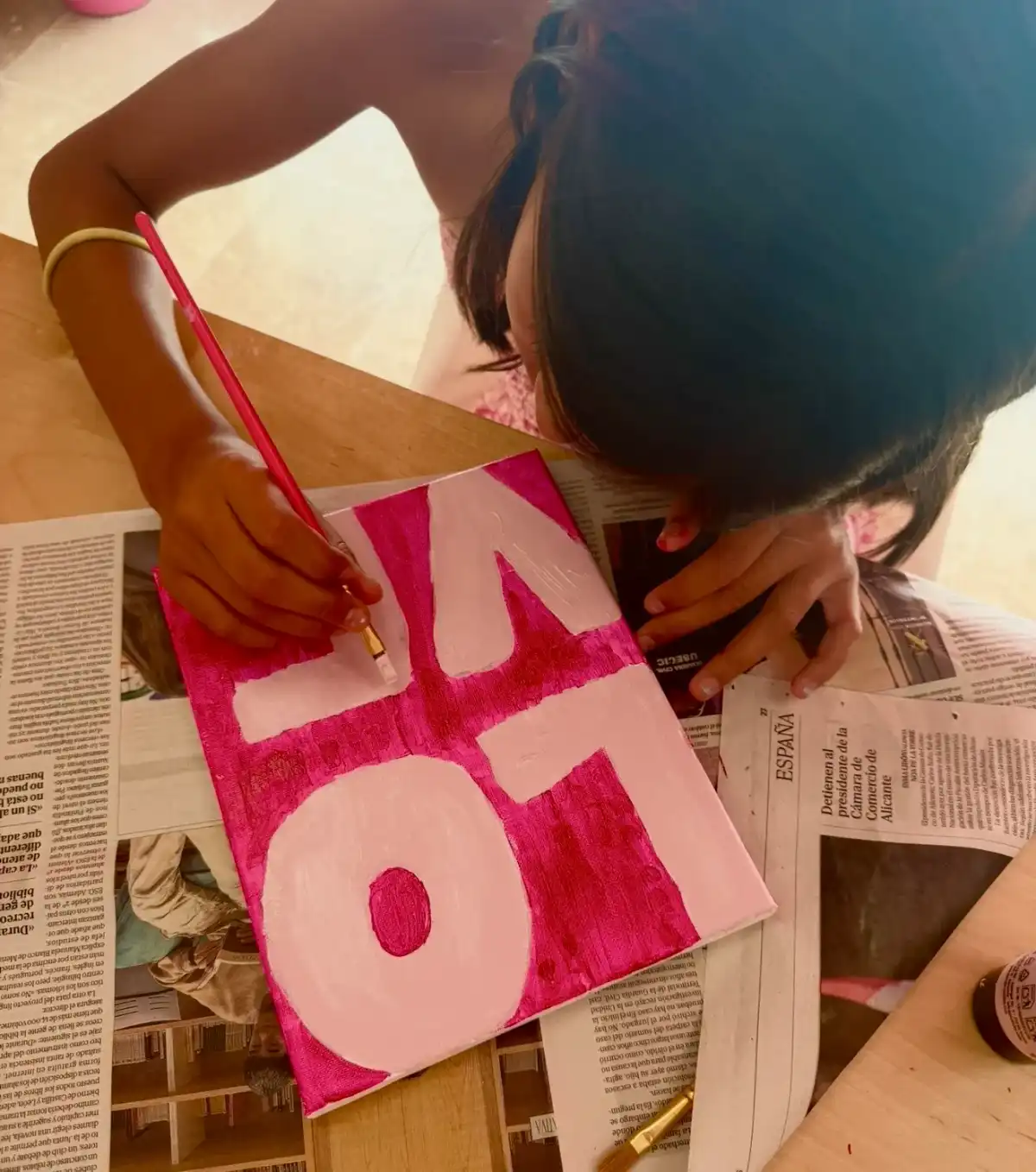 Niña pintando la palabra LOVE en un lienzo