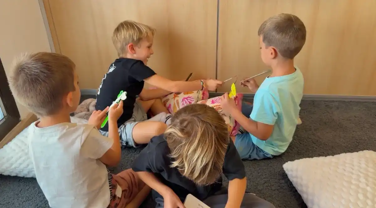 Cuatro niños juegan juntos en clase con figuras de papel