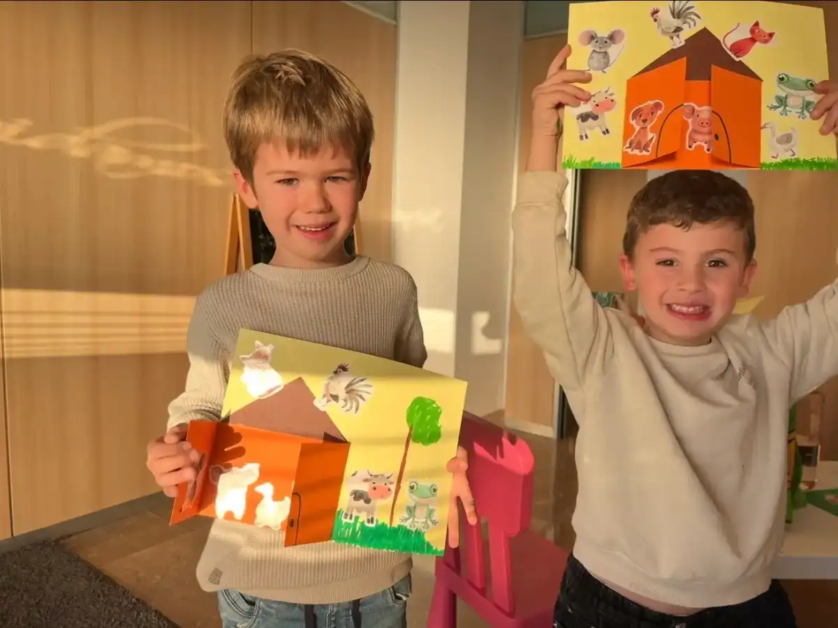 Dos niños enseñan la granja de papel que han hecho en clase de inglés