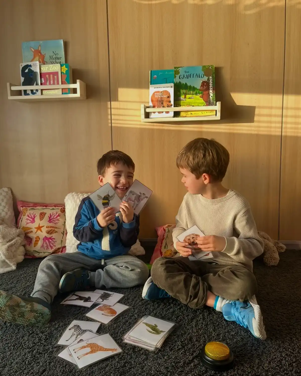 Dos niños se ríen con tarjetas de animales durante una clase de inglés en Play and Learn